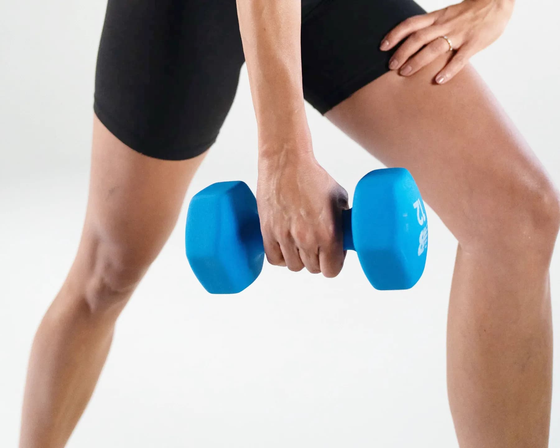 A hand holding a dumbbell at the hip, mid-set